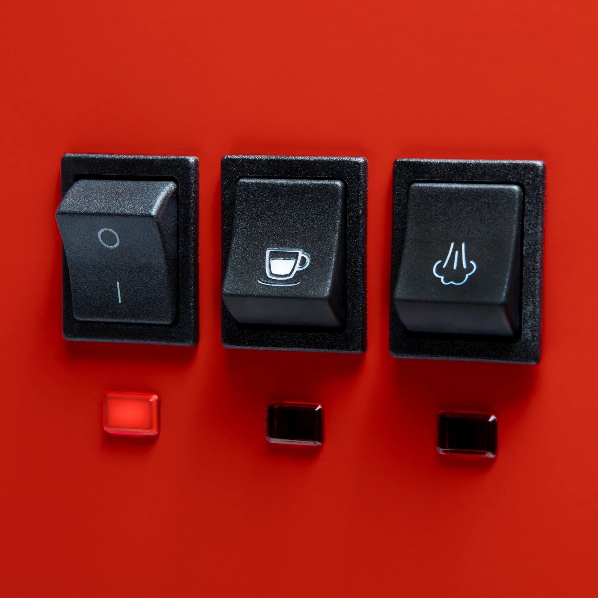 Three black rocker switches mounted on a bright red panel, with small red and black indicator lights below each switch. The center switch has a coffee cup icon, and the right switch has a hand icon.

