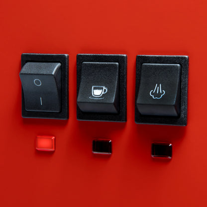 Three black rocker switches mounted on a bright red panel, with small red and black indicator lights below each switch. The center switch has a coffee cup icon, and the right switch has a hand icon.

